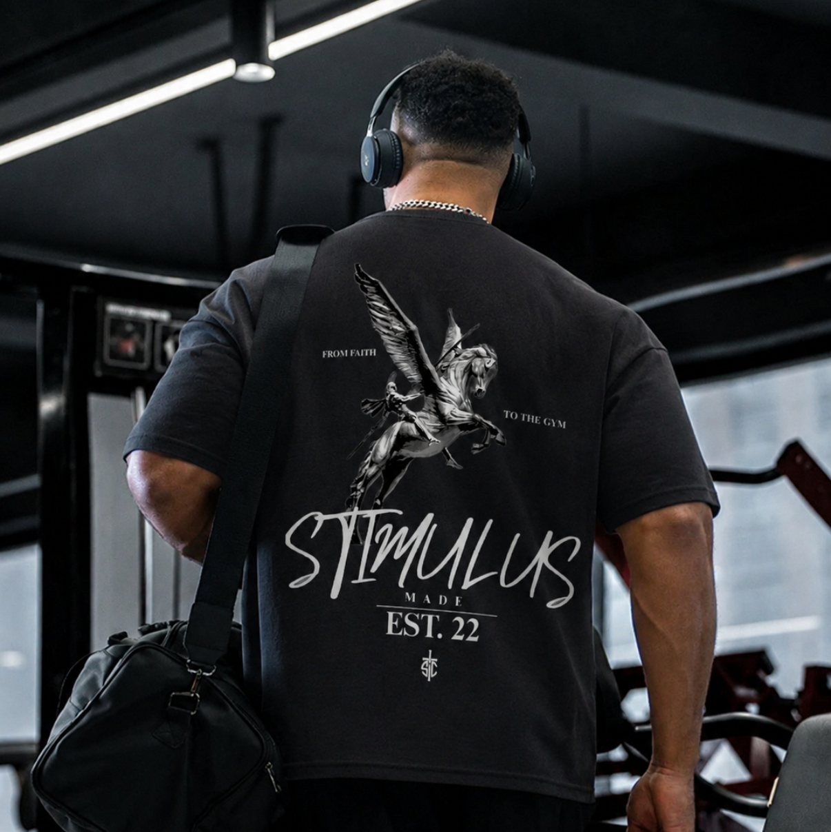 Person wearing a black t-shirt with 'STIMULUS' branding in a gym setting