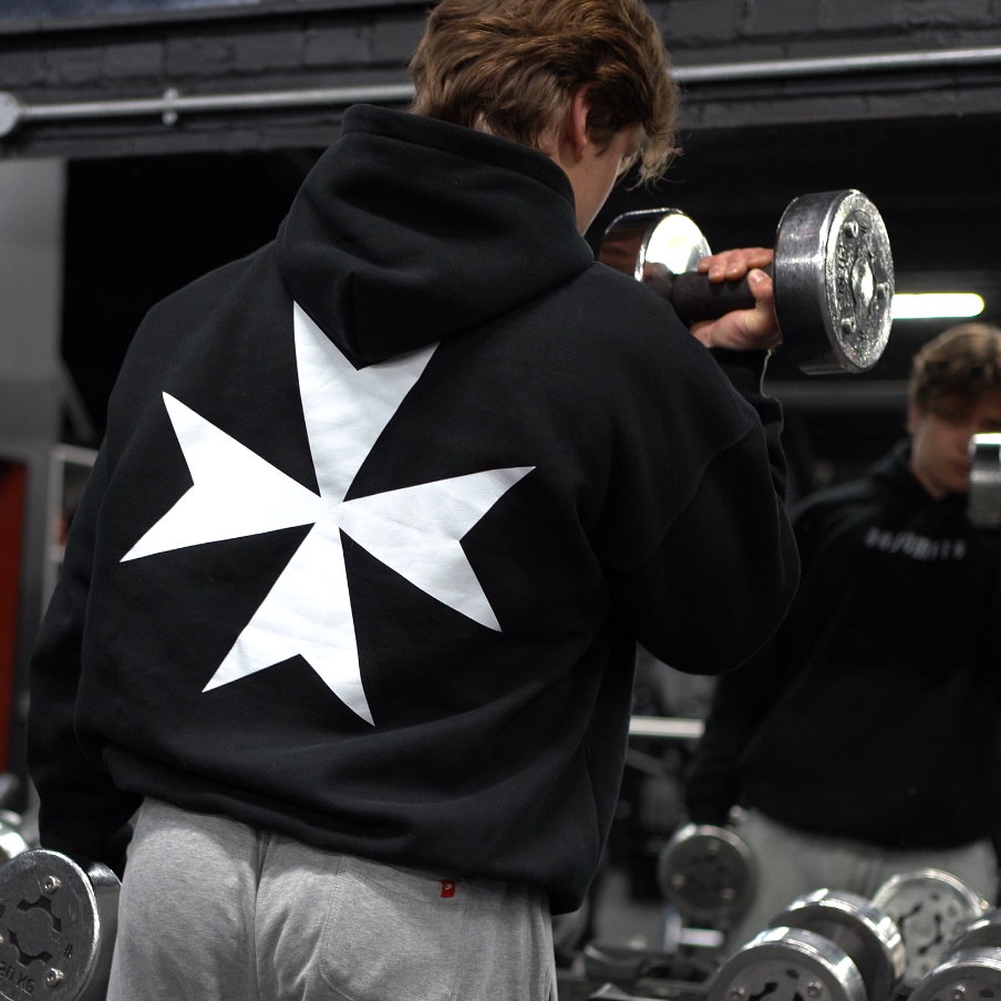 Person wearing a hoodie with a templar design in a gym setting