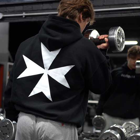 Person wearing a hoodie with a templar design in a gym setting