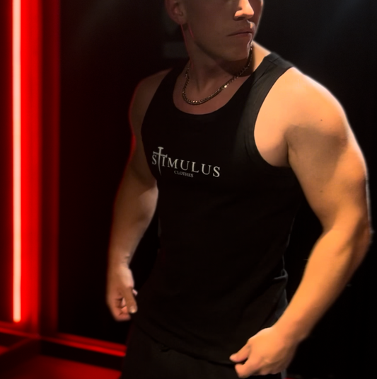 Person wearing a black tank top with visible branding in a room with red lighting.