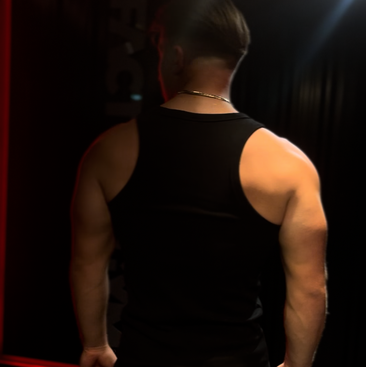 Person wearing a black tank top in a gym setting