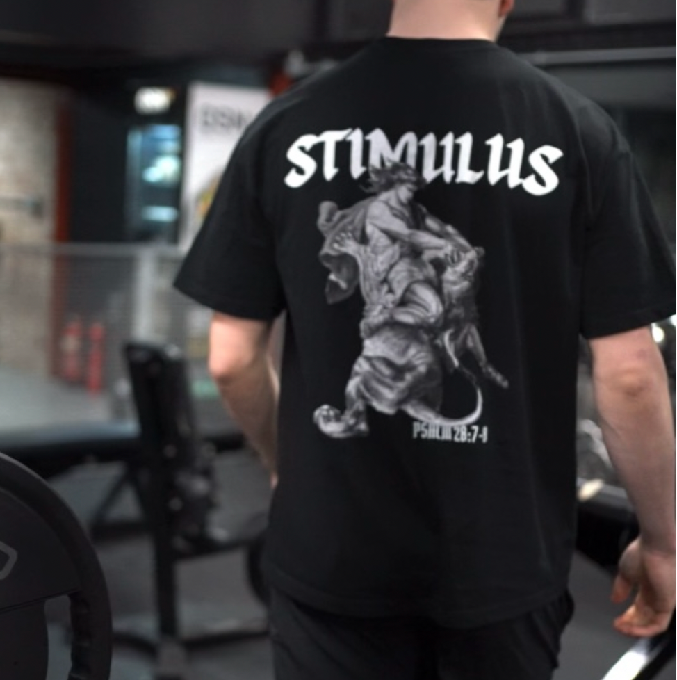 Person wearing a black t-shirt with 'STIMULUS' branding in a gym setting