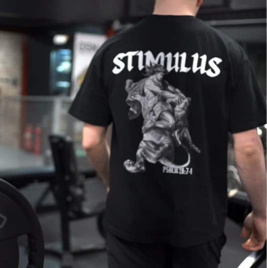 Person wearing a black t-shirt with 'STIMULUS' branding in a gym setting