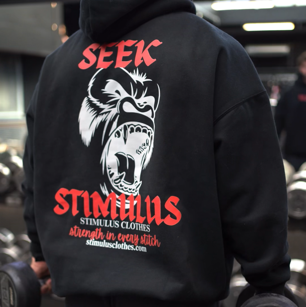 Person wearing a black hoodie with a graphic design and text in a gym setting