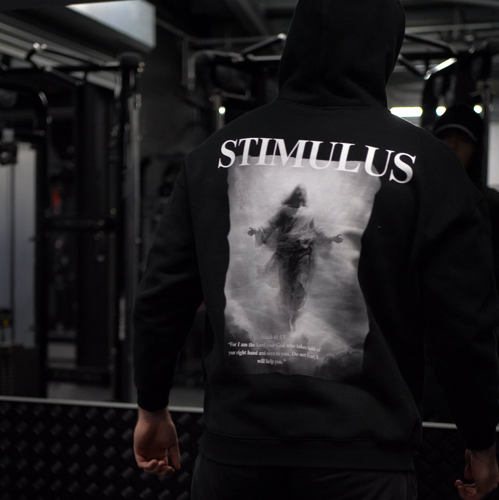 Person wearing a hoodie with 'STIMULUS' branding in a dark setting