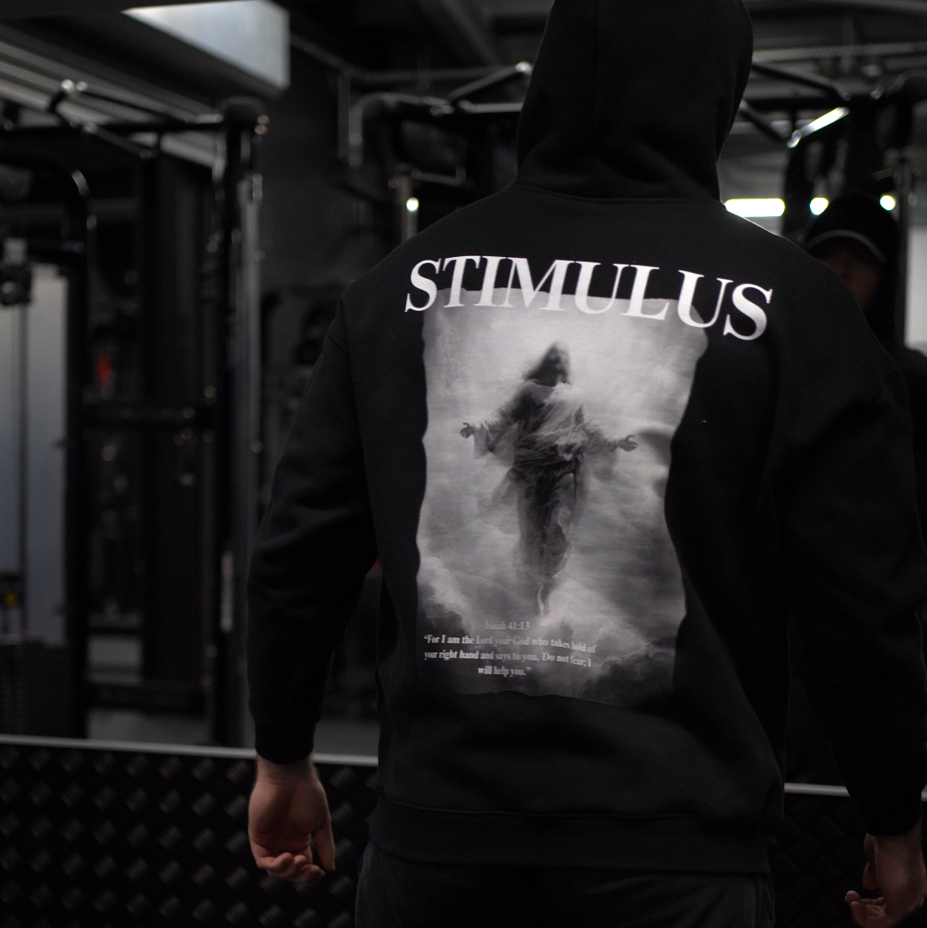 Person wearing a hoodie with 'STIMULUS' branding in a dark setting
