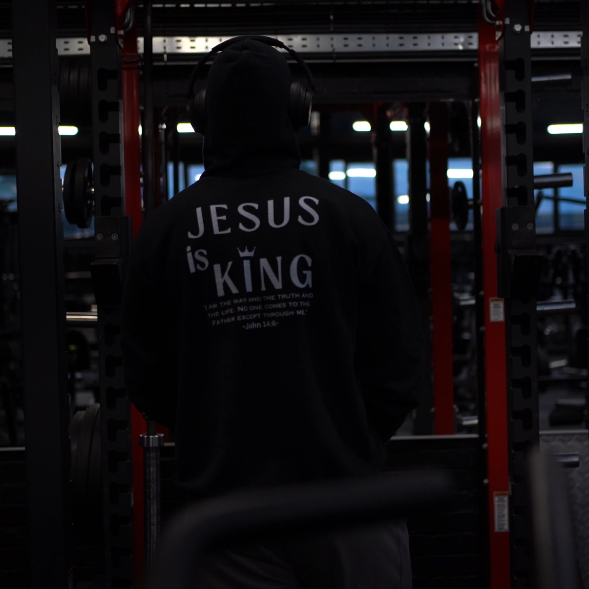 Person wearing a hoodie with 'Jesus is King' text in a dark setting