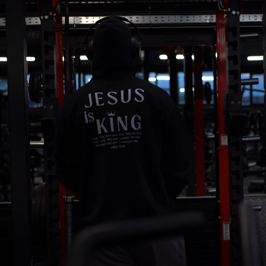 Person wearing a hoodie with 'Jesus is King' text in a dark setting