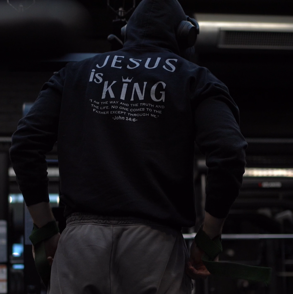 Person wearing a hoodie with 'Jesus is King' text in a gym setting