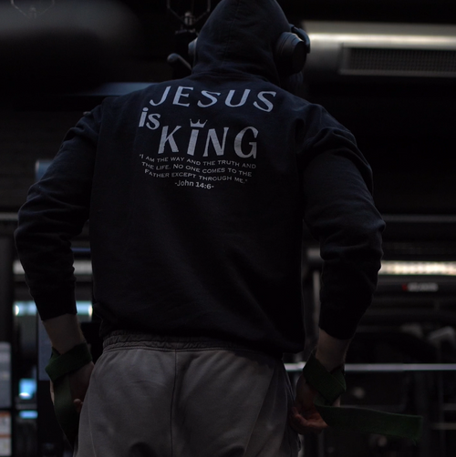 Person wearing a hoodie with 'Jesus is King' text in a gym setting