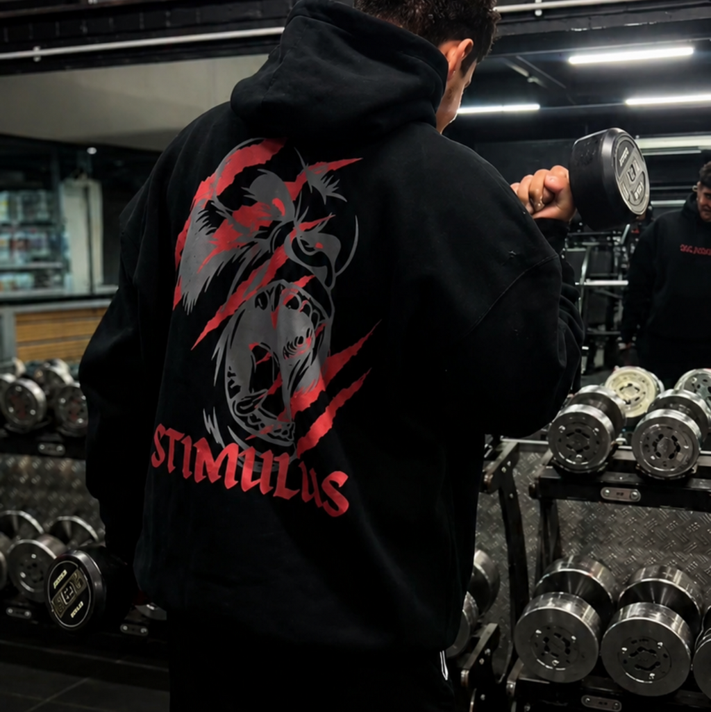 Person wearing a black hoodie with a red and white logo in a gym setting
