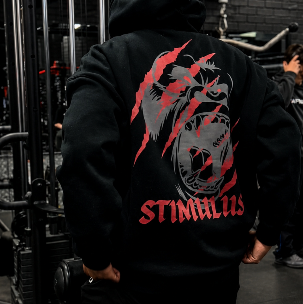 Person wearing a hoodie with a bear graphic and 'STIMULUS' text in a gym setting
